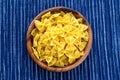 Farfalle macaroni pasta in a wooden bowl on a striped white blue cloth background in the center. Close-up with the top. Royalty Free Stock Photo