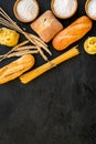 Farinaceous food. Fresh bread and raw pasta near flour in bowl and wheat ears on black background top view copy space Royalty Free Stock Photo