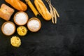 Farinaceous food. Fresh bread and raw pasta near flour in bowl and wheat ears on black background top view copy space Royalty Free Stock Photo