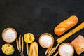 Farinaceous food. Fresh bread and raw pasta near flour in bowl and wheat ears on black background top view copy space