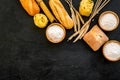 Farinaceous food. Fresh bread and raw pasta near flour in bowl and wheat ears on black background top view copy space Royalty Free Stock Photo