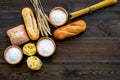 Farinaceous food. Fresh bread and raw pasta near flour in bowl and wheat ears on dark wooden background top view space