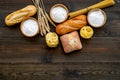 Farinaceous food. Fresh bread and raw pasta near flour in bowl and wheat ears on dark wooden background top view space