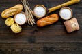 Farinaceous food. Fresh bread and raw pasta near flour in bowl and wheat ears on dark wooden background top view space