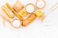 Farinaceous food. Fresh bread and raw pasta near flour in bowl and wheat ears on white stone background top view copy