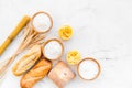 Farinaceous food. Fresh bread and raw pasta near flour in bowl and wheat ears on white stone background top view copy