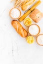 Farinaceous food. Fresh bread and raw pasta near flour in bowl and wheat ears on white stone background top view copy