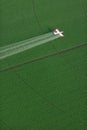 An overhead view of a crop duster spraying green farmland Royalty Free Stock Photo