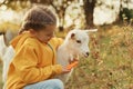 Farm animal. Cute little girl feeding goatling on pasture