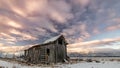 Farm barn in winter with morning colored clouds over it
