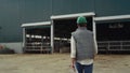 Farm breeder walking modern cowshed rear view. Agriculture facility building