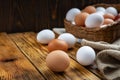 Farm eggs white and brown lie on a wooden table and in a basket, close-up, low light, selective focus, shallow depth of Royalty Free Stock Photo