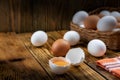 Farm eggs white and brown lie on a wooden table and in a basket, close-up, low light, selective focus, shallow depth of Royalty Free Stock Photo