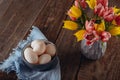 Farm Fresh white eggs in ceramic grey bowl on vintage blue napkin and vase with fresh pink and yellow tulips on the rustic wooden Royalty Free Stock Photo