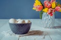 Farm Fresh white eggs in ceramic grey bowl on vintage napkin and vase with fresh pink and yellow tulips on the white wooden table Royalty Free Stock Photo