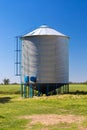 Farm grain silo for agriculture. Cylindrical metal structure Next to the cultivated field. Royalty Free Stock Photo