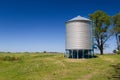 Farm grain silo for agriculture. Cylindrical metal structure Next to the cultivated field. Royalty Free Stock Photo