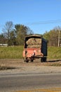 A farm hay wagon filled with silage waiting on the edge of a farm field