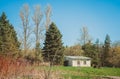 A lonely white stone house in a forest and field.