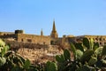 A farm house , buildings and church spire on the Mediterranean island of Gozo.