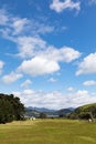 Farm house and paddock in rural Otago Peninsula, New Zealand, with coastline and mountains in distance