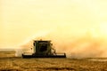 A combine harvesting a ripe wheat field at sunset. Royalty Free Stock Photo