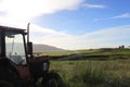 Farm meadows with tractor, grass and blue skies