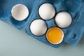 Farm natural products. Fresh white chicken eggs in eco-packaging on a blue background. Broken egg with yolk in the shell. Top view Royalty Free Stock Photo
