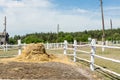 Farm scene with wooden log fence, bale of hay and barn. Countryside rural landscape Royalty Free Stock Photo