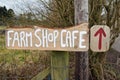 Farm shop and cafe sign with red arrow and rural background