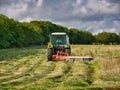 A farm tractor carrying out silage operations in a grassy field in Kent, England, UK