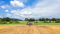 A farm tractor cultivating a harvested field against  a blue sky with clouds on a sunny summer day Royalty Free Stock Photo