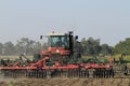 Farm Tractor in a farm field working in the field with dirt in the air and blue sky Royalty Free Stock Photo