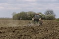 Farm tractor milling the soil on agricultural field.