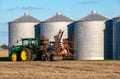 A farm tractor parked at grain storage bins