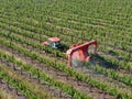 Farm tractor spraying pesticides & insecticides herbicides over green vineyard field Royalty Free Stock Photo