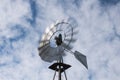 Farm windmill spinning on a sunny day with clouds Royalty Free Stock Photo