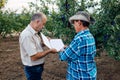 Farmer and agronomist. Senior farmer signs contract to sell plum fruit.