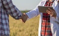 Farmer and agronomist shaking hands in field