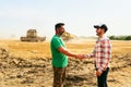 Farmer and agronomist shaking hands standing in a wheat field after agreement. Agriculture business contract concept