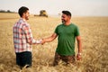 Farmer and agronomist shaking hands in wheat field after agreement. Agriculture business contract concept. Corporate Royalty Free Stock Photo