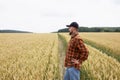 A farmer agronomist stands in a wheat field and inspects the wheat. Harvest time Royalty Free Stock Photo