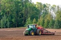 The farmer in the autumn treats the fields with the tractor and enriches them with mineral fertilizers.