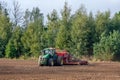 The farmer in the autumn treats the fields with the tractor and enriches them with mineral fertilizers.