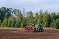 The farmer in the autumn treats the fields with the tractor and enriches them with mineral fertilizers.