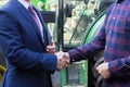 Farmer And Businessman Shaking Hands With Tractor In Background Royalty Free Stock Photo