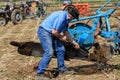 Farmer cleaning mud off plough of old vintage tractors at ploughing match Royalty Free Stock Photo