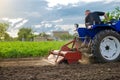 A farmer is cultivating a field before replanting seedlings. Milling soil, crushing and loosening ground before cutting rows