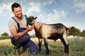 Farmer with cute goatling outdoors. Baby animal