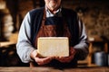 A farmer demonstrates a piece of cheese he made with his own hands. Homemade cheese production on a farm. Natural product. Close-